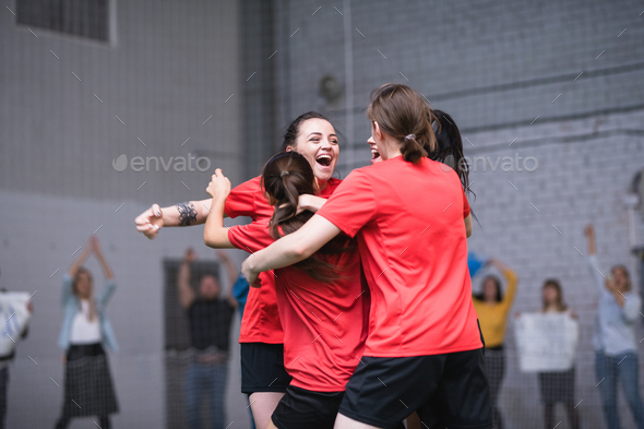 Ecstatic girls in sports uniform embracing after successful goal during game