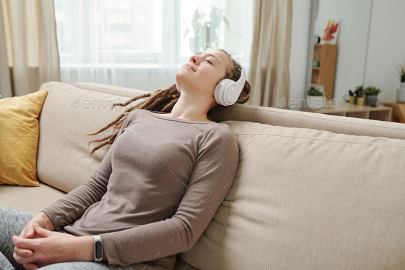 Happy young relaxed woman with headphones listening to meditation music
