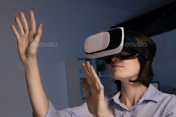 Contemporary employee with vr headset standing in front of virtual display