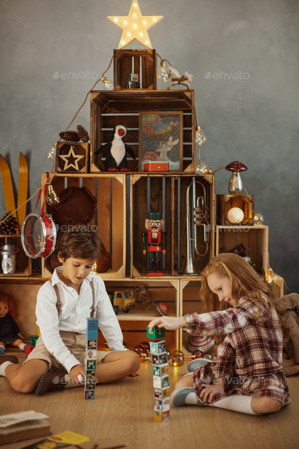 Two Kids Playing With Toys Near the Christmas Tree - Stock Photo - Images