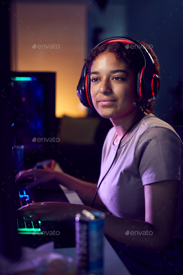 Teenage Girl With Caffeine Energy Drink Gaming At Home Using Dual Computer Screens At Night