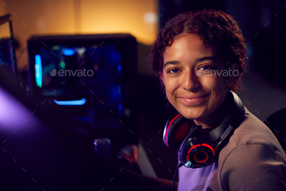 Portrait Of Teenage Girl With Headset Gaming At Home Using Dual Computer Screens