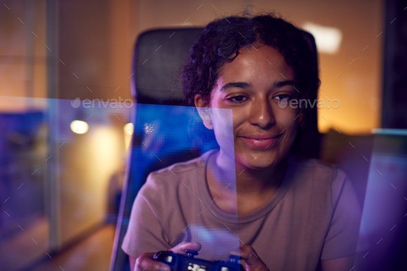 Teenage Girl With Game Pad Sitting In Chair and Gaming At Home With Screen Reflection