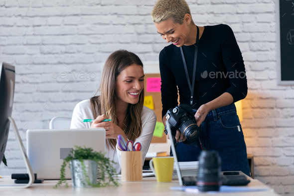 Smiling entrepreneur women reviewing last photographs in the camera in ...