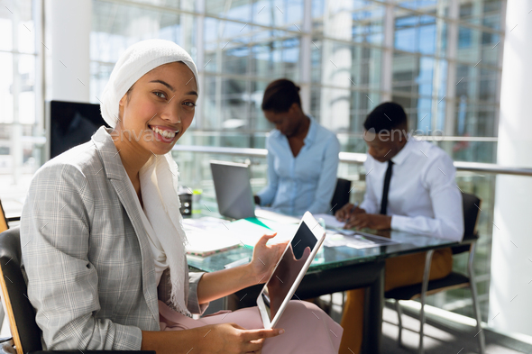 Businesswoman in hijab using digital tablet at desk in office