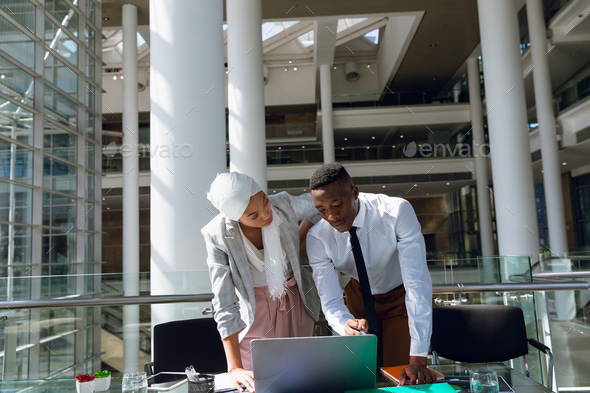 Male and female executives discussing over laptop at desk - Stock Photo - Images