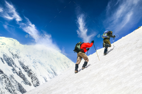 Two mountain trekkers on steep snowed hill with dramatic sky background, Himalayas - Stock Photo - Images