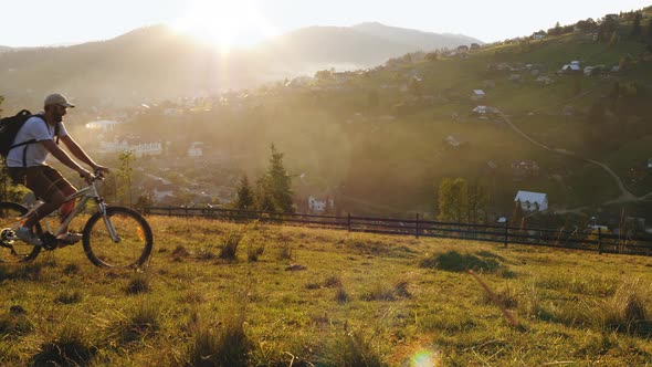 A Man on a Bicycle Stopped To Admire the Mountain Landscape alt