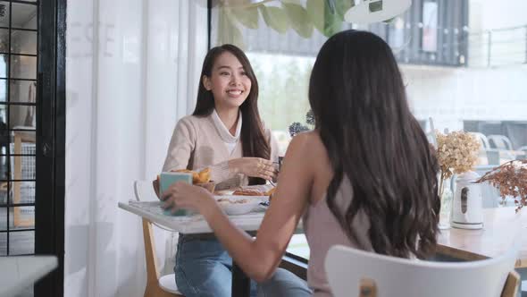 Two young Asian women friends talking at a coffee shop
