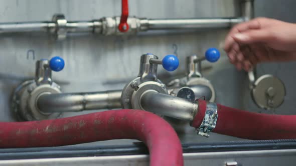 Crop View of Worker of Beer Manufacture Holding Blue Level of Boiler System with Rubber Pipes
