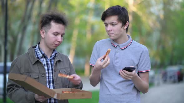 Two Friends are Eating Pizza Outdoors