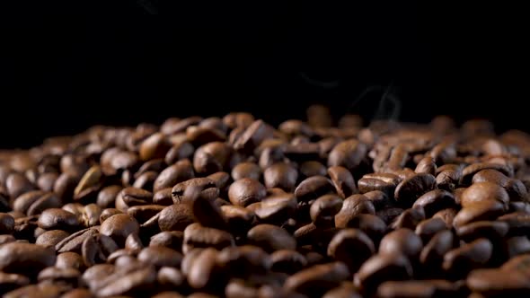 Roasted coffee beans with smoke. Slow motion of arabica coffee seeds falling. alt