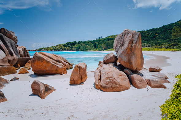 Couple on tropical beach lagoon with granite boulders in the turquoise water and a pristine white - Stock Photo - Images