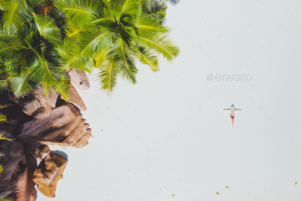 Aerial photo of young woman laying on exotic tropical beach with white sand. Girl sunbathing and - Stock Photo - Images