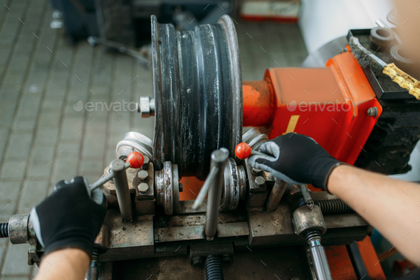Mechanic works with wheel on disc rolling machine - Stock Photo - Images