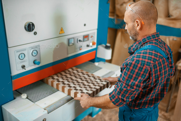 Carpenter works on woodworking machine, factory - Stock Photo - Images