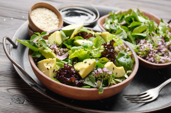 Clay dish with salad of avocado, green and violet lettuce - Stock Photo - Images