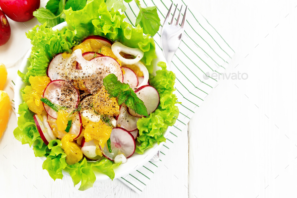 Salad of radish and orange with mint on light board top - Stock Photo - Images