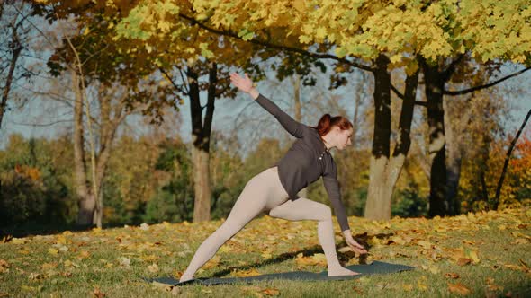 Young Woman Doing Warrior and Extended Side Angle Yoga Poses in Park on a Mat
