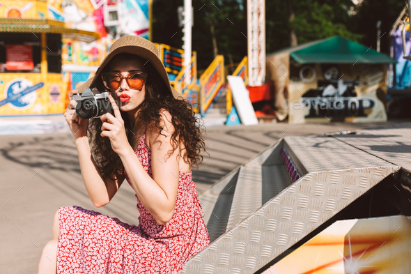 Beautiful lady in sunglasses and hat spending time in amusement park with little camera - Stock Photo - Images
