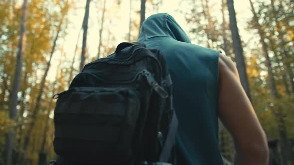 Morning workout. Back view of young man with backpack going to the forest gym, outdoors