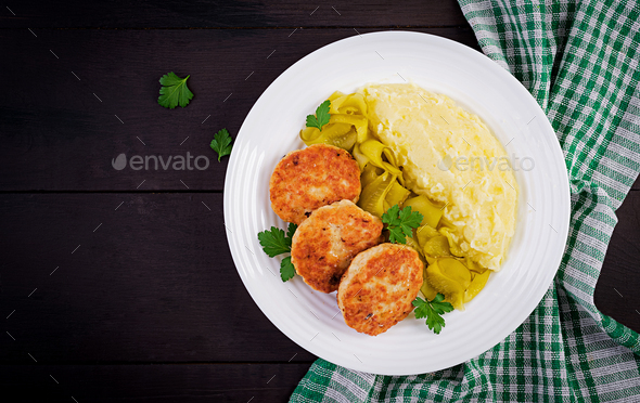 Homemade fried cutlets/meatballs with mashed potatoes and pickled cucumber on white plate. - Stock Photo - Images