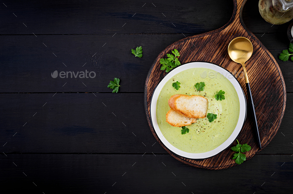 Homemade broccoli cream soup with croutons in white bowl on wooden board. - Stock Photo - Images