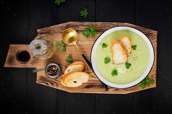 Homemade broccoli cream soup with croutons in white bowl on wooden board - Stock Photo - Images