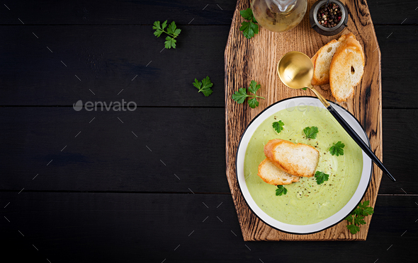 Homemade broccoli cream soup with croutons in white bowl on wooden board - Stock Photo - Images