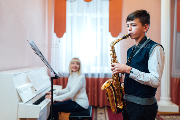 boy learns to play the saxophone in a music lesson
