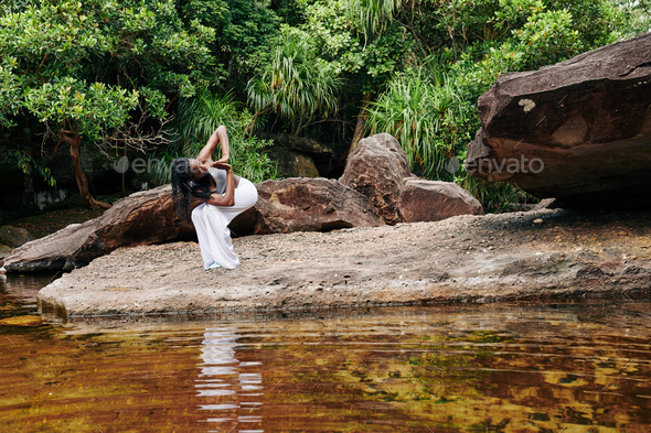 Woman exercising in forest by the creek - Stock Photo - Images