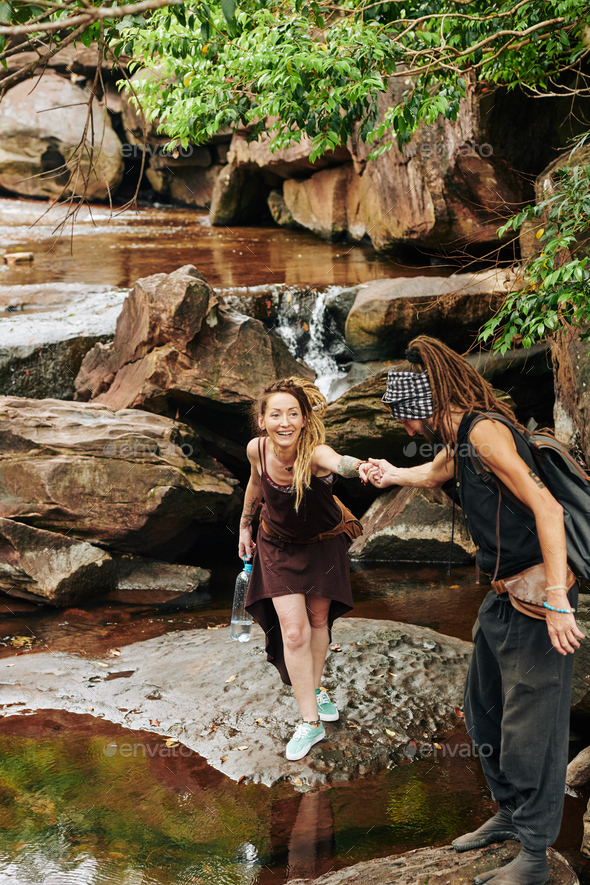 Happy couple overstepping stream - Stock Photo - Images