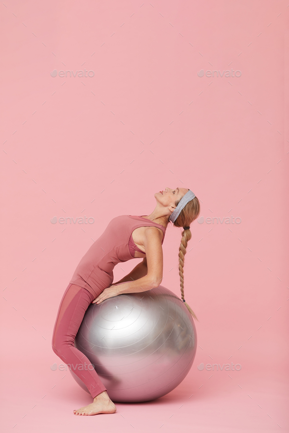 Mature Woman Stretching against Pink - Stock Photo - Images