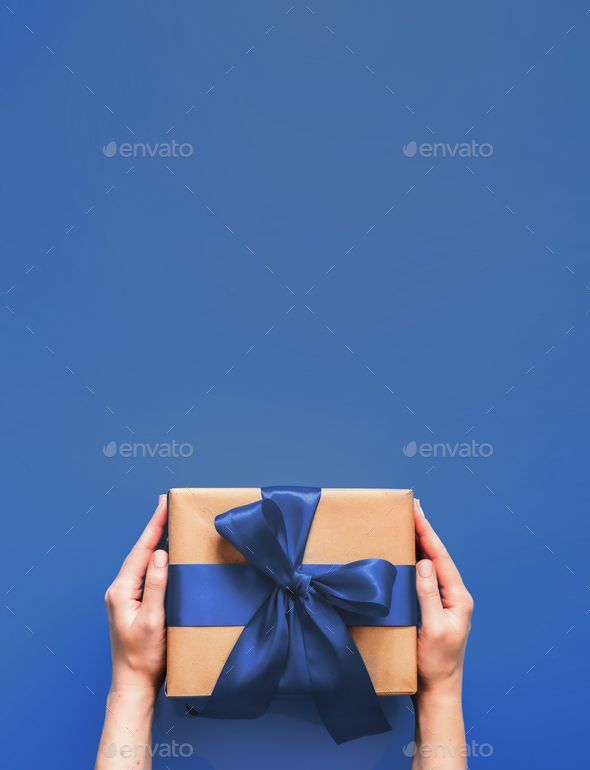Female hands hold gift box on blue 2020 color - Stock Photo - Images