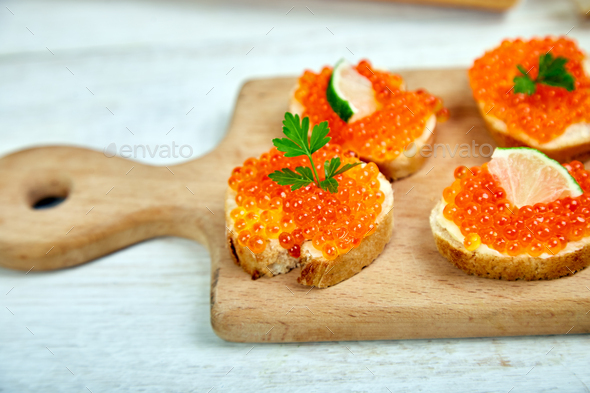 Salmon red caviar in bowl and Sandwiches with on wooden cutting board - Stock Photo - Images
