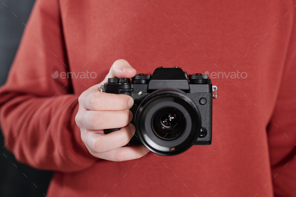 Hands of contemporary male photographer with new photocamera by chest - Stock Photo - Images