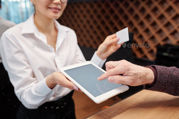 Hand of mature businessman pointing at tablet display to put his signature