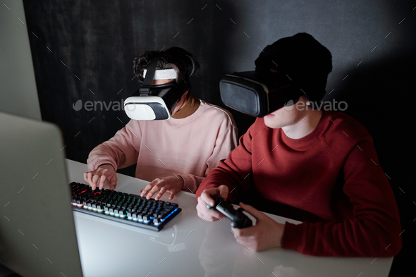 Two contemporary teenagers in vr headsets playing computer games - Stock Photo - Images