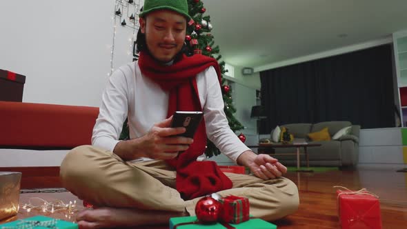 Smile Asian man using mobile taking a photo gift box and upload to the internet in the living room.