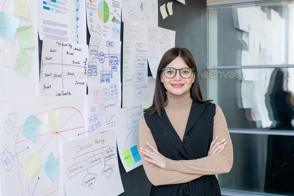 Smiling economist in smart casual and eyeglasses analyzing financial information - Stock Photo - Images