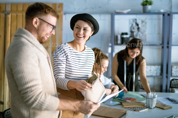Cheerful female and her colleague choosing textile for new fashion collection - Stock Photo - Images