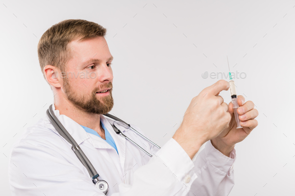 Bearded young successful doctor with syringe going to make injection - Stock Photo - Images