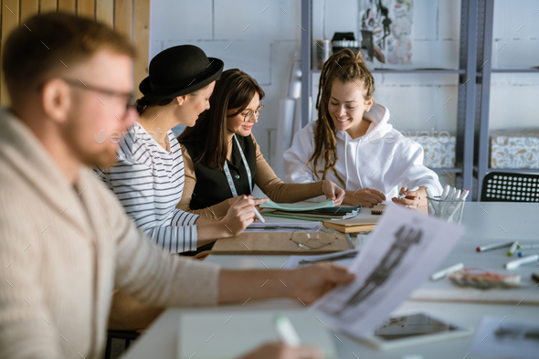 Group of happy young women discussing creative ideas while working in studio - Stock Photo - Images