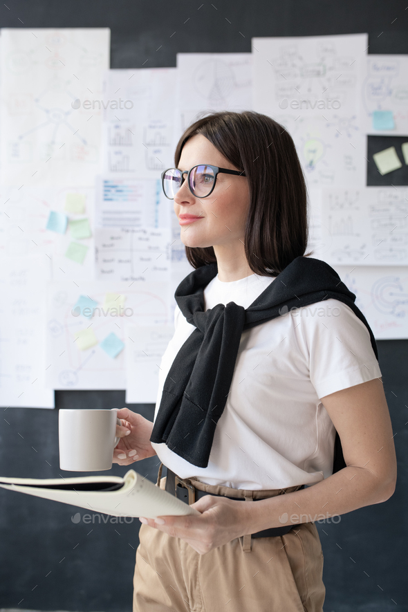 Young casual businesswoman with drink and copybook preparing for seminar - Stock Photo - Images