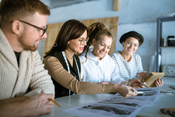 Young creative designers discussing fashion sketches while working in studio - Stock Photo - Images