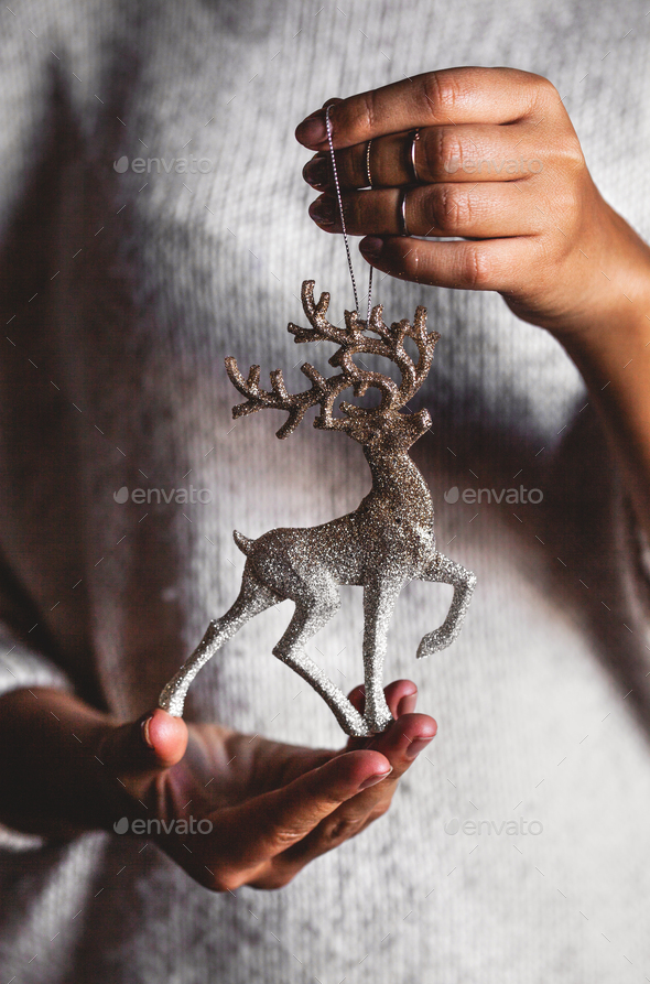 Woman in warm sweater holding toy deer decorative ball in hands, copy space. Christmas, new year - Stock Photo - Images