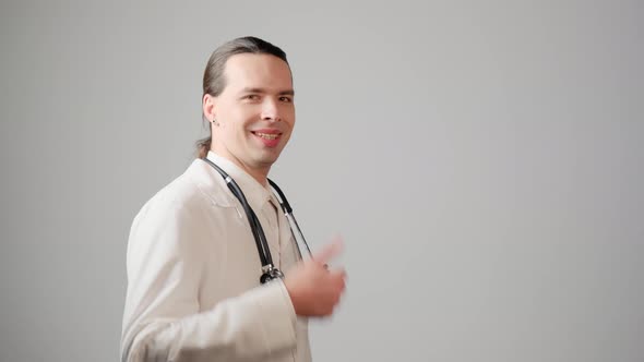 A Male Doctor in a Lab Coat Shows a Thumbsup Gesture and Looks at the Camera