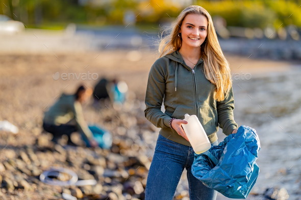 Volunteer holding bottle and garbage bag at beach - Stock Photo - Images