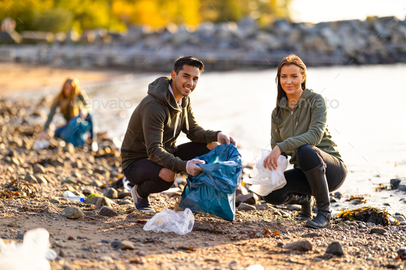 Portrait of smiling environmental protection volunteers cleaning beach - Stock Photo - Images