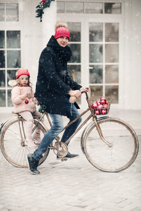 Dad and daughter in red hats riding a bike - Stock Photo - Images